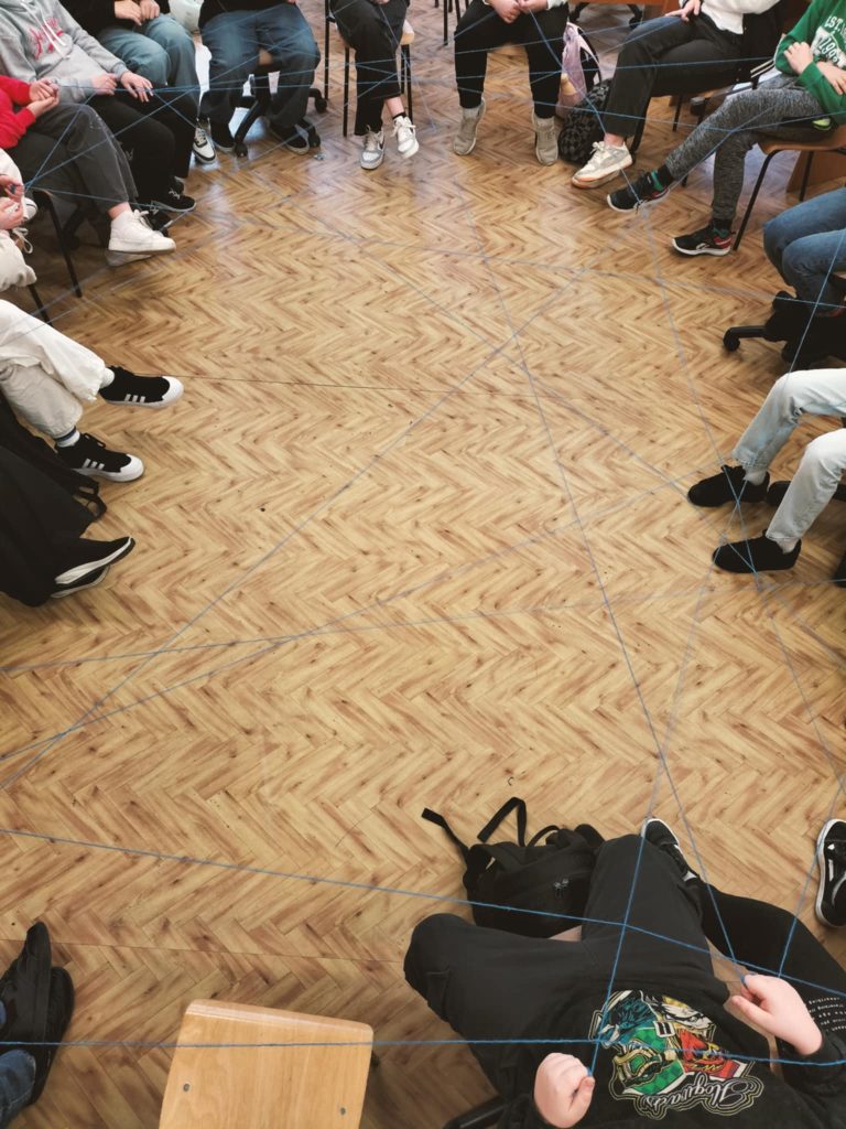 Zdjęcie uczestników warsztatów siedzących w okręgu w szkole podstawowej w Woli Małej