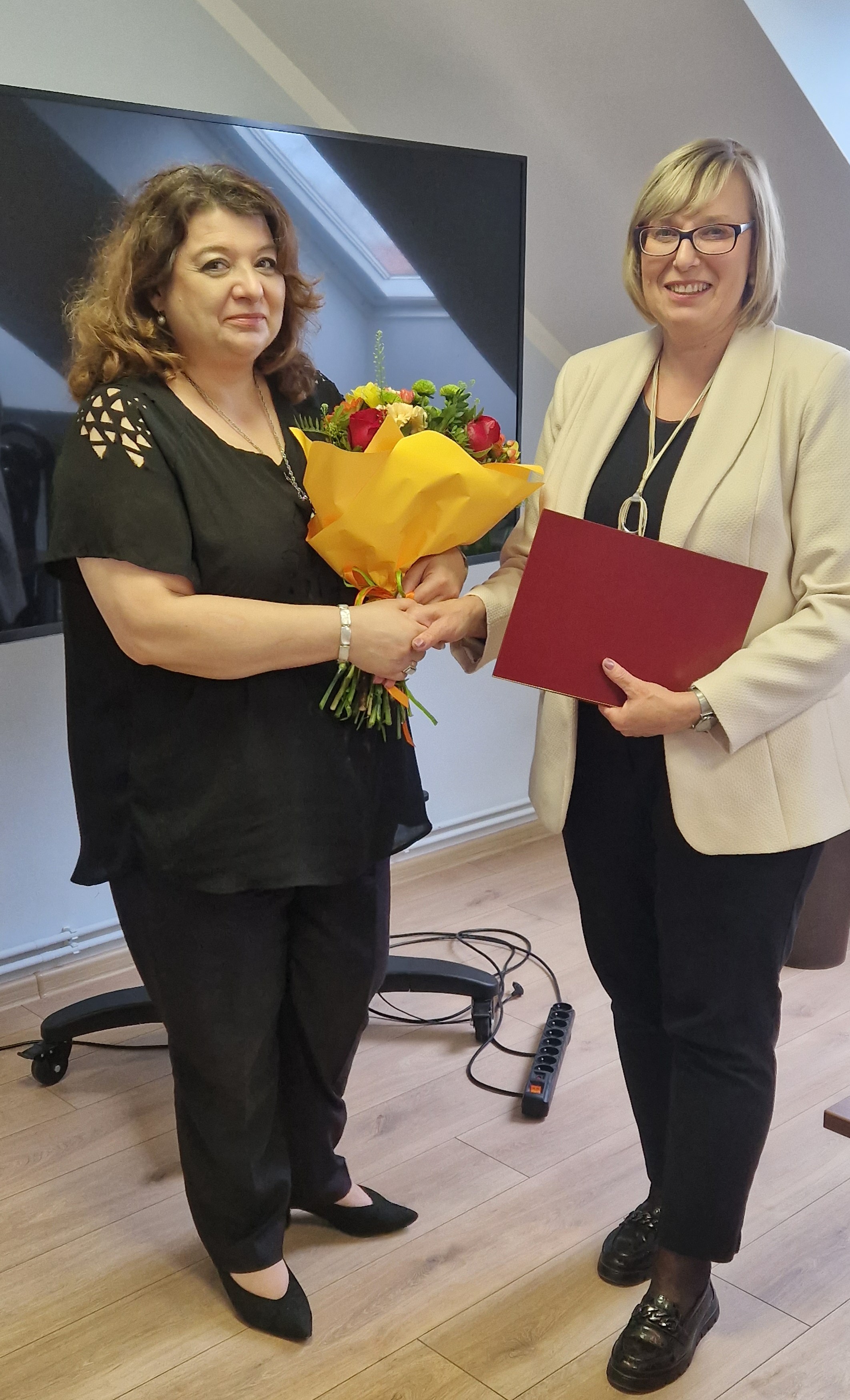 Zdjęcie przedstawiające wręczenie kwiatów mgr Joanny Woźniak z okazji 25-lecia pracy.